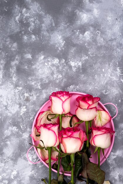 Ramo rojo de la flor de la rosa del blanco con la caja de regalo rosada en la tabla de piedra.