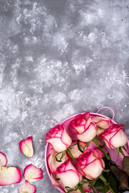 Ramo rojo de la flor de la rosa del blanco con la caja de regalo rosada en la tabla de piedra.