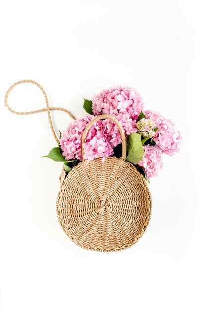 Ramo rosa de hortensias en una bolsa de paja sobre fondo blanco concepto floral mínimo endecha plana