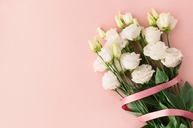 Ramo de rosas blancas con lazo rosa.