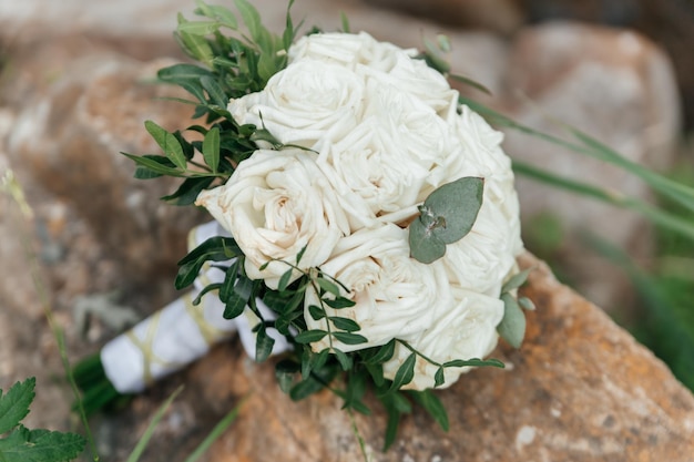 El ramo de rosas blancas de la novia en un primer plano de una superficie de piedra