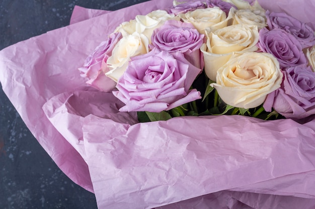 Ramo de rosas blancas y púrpuras increíbles frescas en papel artesanal sobre fondo blanco.