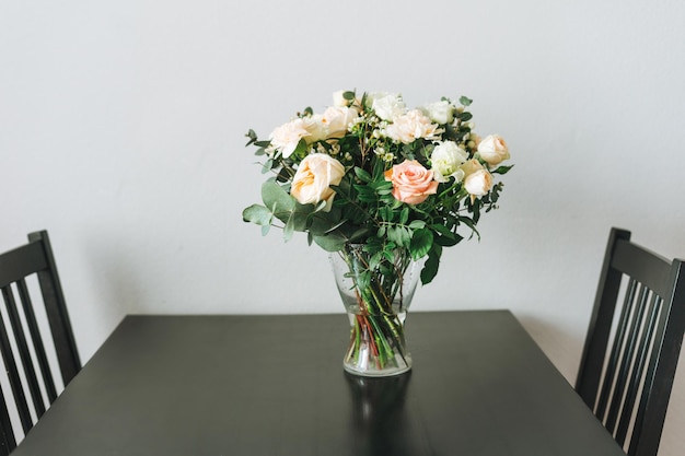 Ramo de rosas blancas y rosas, verdes y otras flores en la mesa de la cocina, decoración del hogar