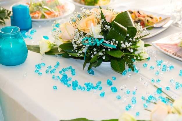 Ramo de rosas y decoración turquesa en la mesa de boda.