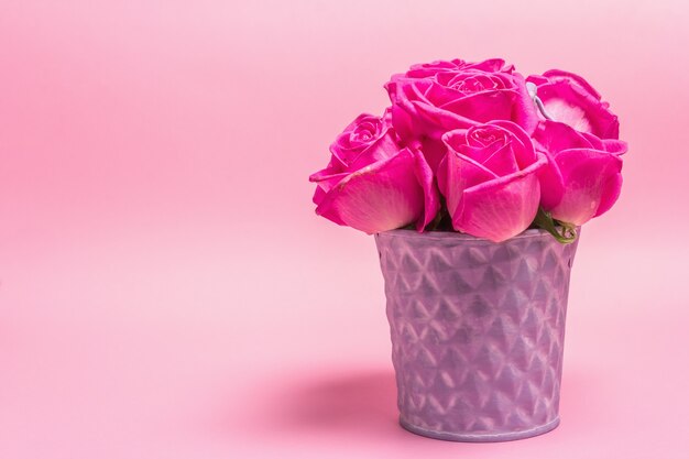 Ramo de rosas frescas en un cubo. El concepto festivo para bodas, cumpleaños, 8 de marzo, día de la madre o San Valentín. Tarjeta de felicitación, fondo rosa claro