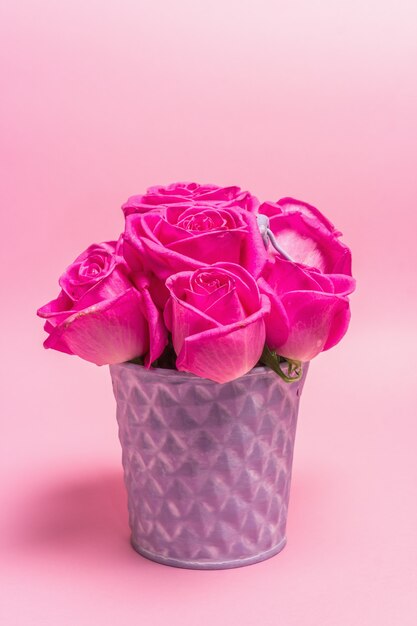 Ramo de rosas frescas en un cubo. El concepto festivo para bodas, cumpleaños, 8 de marzo, día de la madre o San Valentín. Tarjeta de felicitación, fondo rosa claro