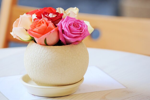 Un ramo de rosas en un jarrón redondo.