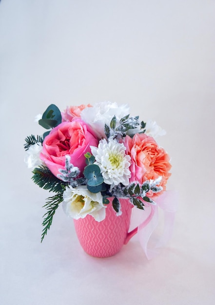Ramo de rosas lujosas en una taza de cerámica pastel sobre un fondo claro con una sombra natural suave