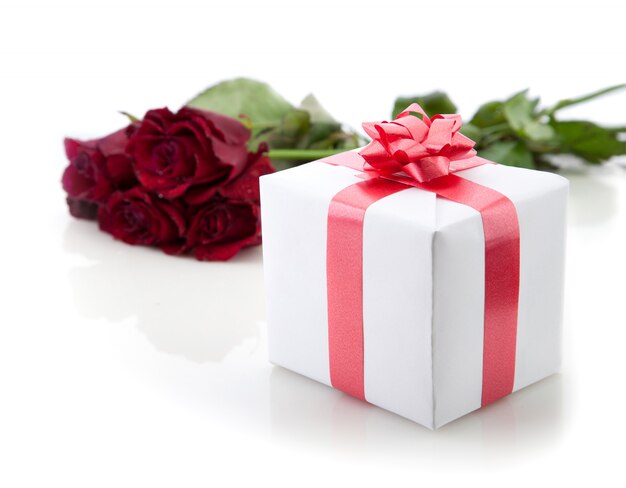 Un ramo de rosas y un regalo romántico en blanco.
