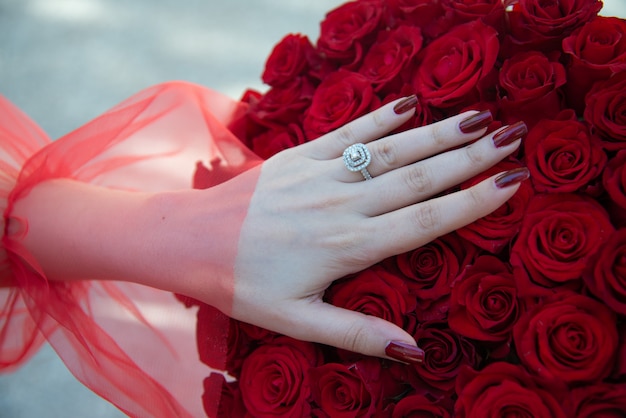 Ramo de rosas rojas con anillo de compromiso. Novia con ramo de flores y anillo de compromiso.
