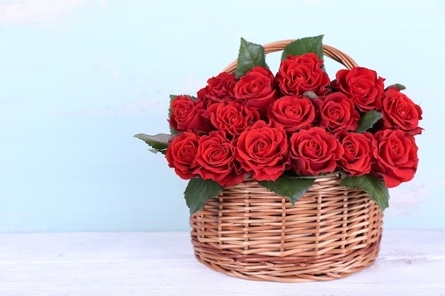 Ramo de rosas rojas en canasta sobre fondo de madera