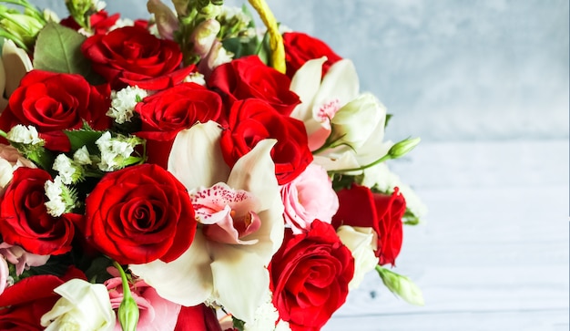 Ramo de rosas rojas, eustoma, orquídea. Naturaleza muerta con flores de colores. Dia de san valentin con rosas