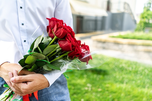 Un ramo de rosas rojas en manos de un hombre de cerca.