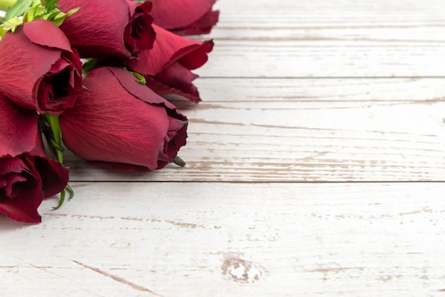 Ramo de rosas rojas sobre fondo de madera pintada en blanco con espacio de copia