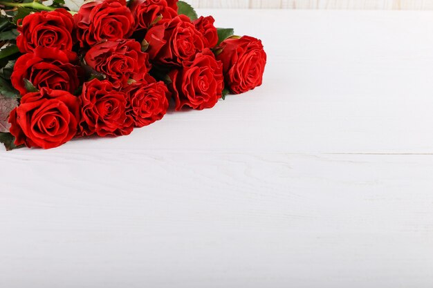 Ramo de rosas rojas sobre una mesa de madera blanca