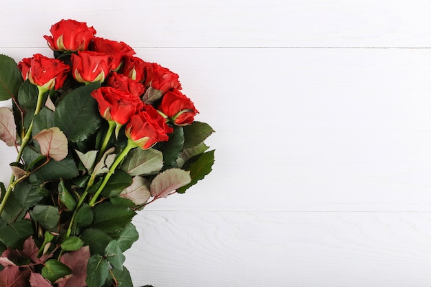 Ramo de rosas rojas sobre una mesa de madera blanca