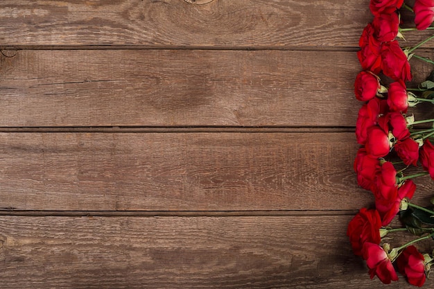 Ramo de rosas rojas sobre la vista superior de la mesa de madera con flores de espacio de copia