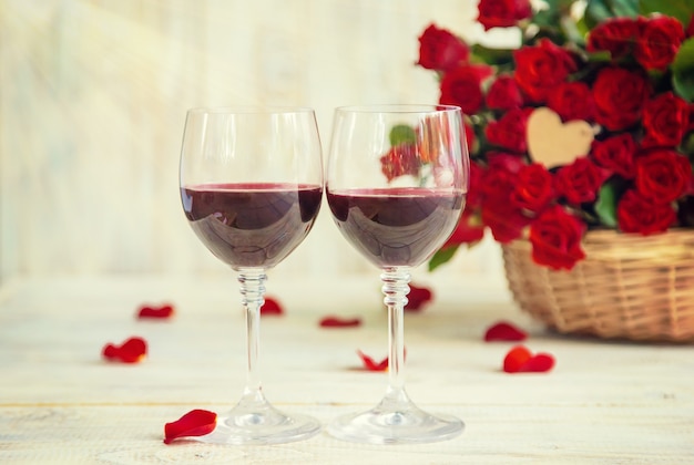 Un ramo de rosas rojas y vino tinto en copas. Día de San Valentín. Enfoque selectivo. Fiesta.