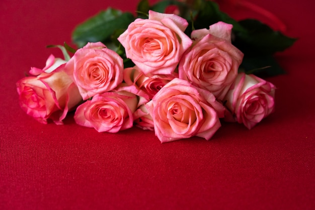 Un ramo de rosas rosadas está sobre la mesa roja. espacio para texto