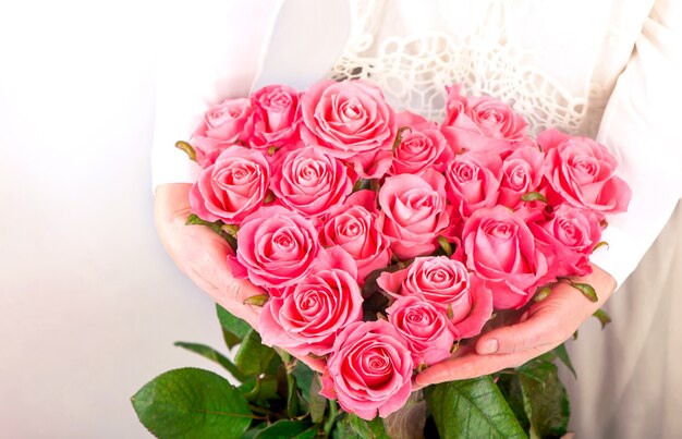 Foto ramo de rosas rosadas en forma de corazón en manos femeninas