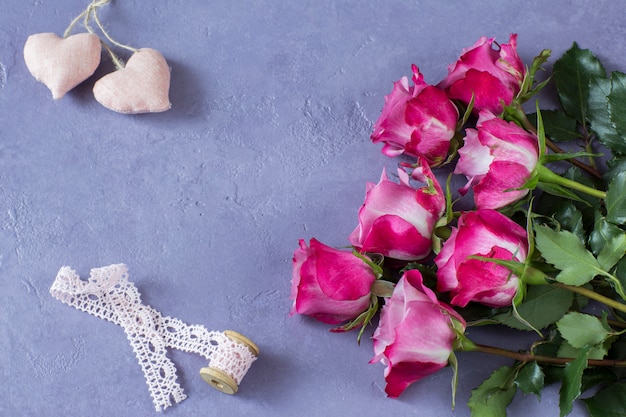 Ramo de rosas rosadas, lazo de encaje y dos corazones decorativos.