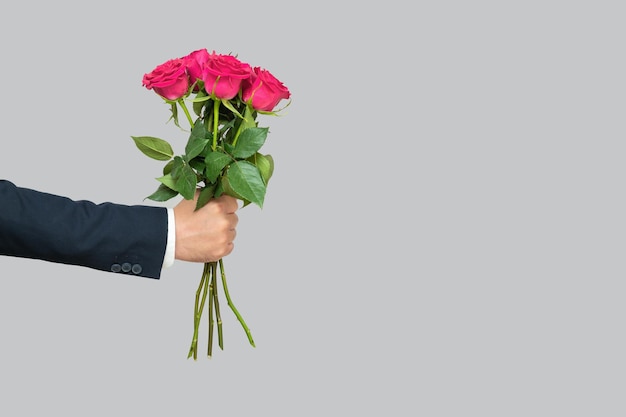 ramo de rosas rosadas en la mano de un hombre