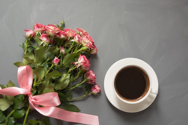 Ramo de rosas rosadas y taza de café en gris