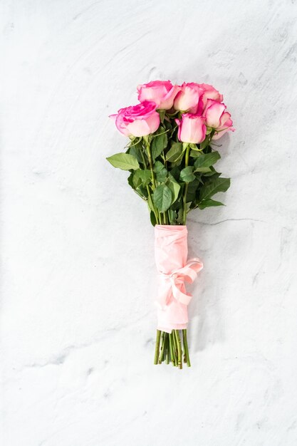 Ramo de rosas rosas envueltas en papel de regalo rosa con una cinta rosa sobre un fondo de hormigón