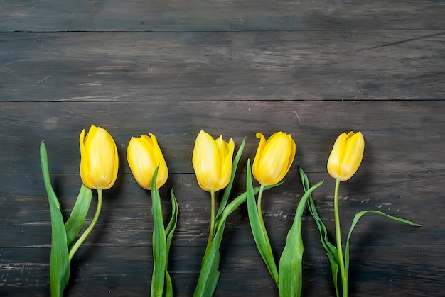 Ramo de tulipanes amarillos con una cinta amarilla en un fondo de madera