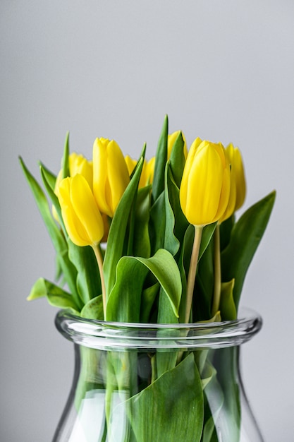 Un ramo de tulipanes amarillos en un jarrón de vidrio.