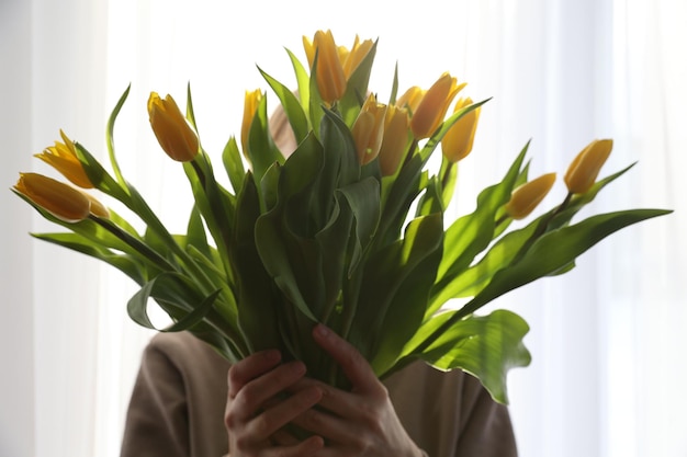 Un ramo de tulipanes amarillos en la mano.