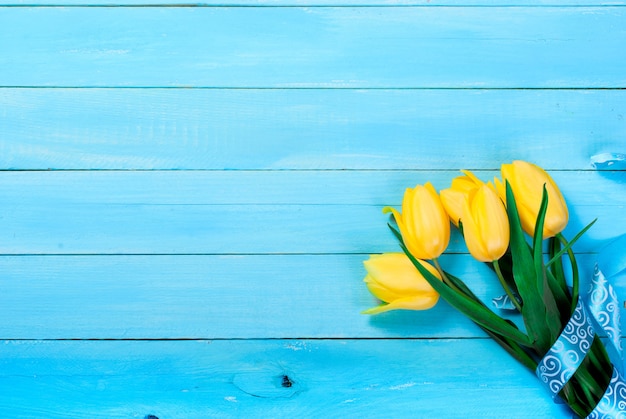 Ramo de tulipanes amarillos sobre un fondo azul de madera