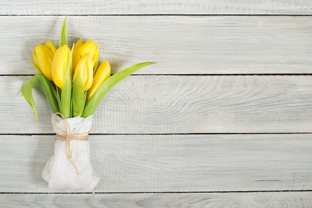 Ramo de tulipanes amarillos sobre una mesa de madera blanca