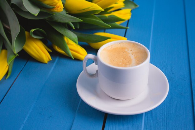 Ramo de tulipanes amarillos y una taza de café.