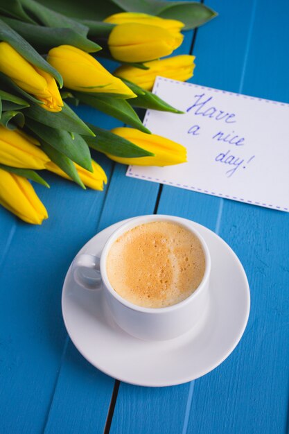 Ramo de tulipanes amarillos y una taza de café.