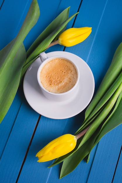 Ramo de tulipanes amarillos y una taza de café.