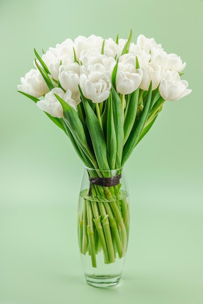 Foto un ramo de tulipanes blancos en un fondo verde pastel en flor