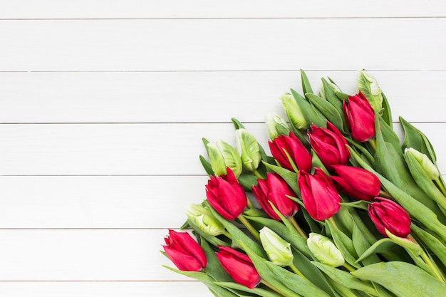 Ramo de tulipanes blancos y rojos en madera blanca