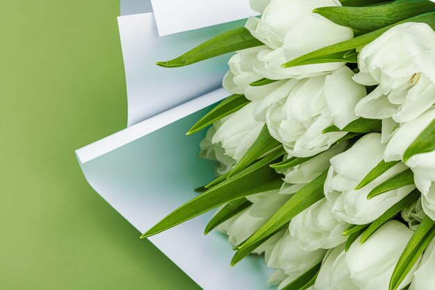Un ramo de tulipanes blancos sobre un fondo verde pastel con flores en flor concepto festivo