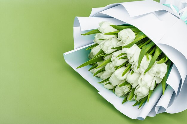 Un ramo de tulipanes blancos sobre un fondo verde pastel con flores en flor concepto festivo