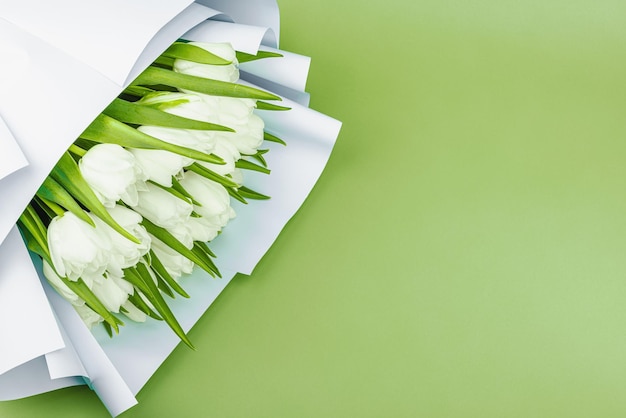 Un ramo de tulipanes blancos sobre un fondo verde pastel con flores en flor concepto festivo