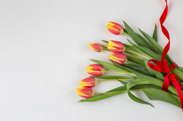 Ramo de tulipanes y una cinta roja.