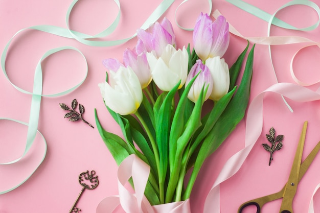 Ramo de tulipanes en un fondo en colores pastel rosado.