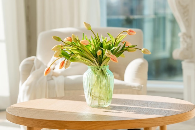 Un ramo de tulipanes en un hermoso jarrón en casa en un interior moderno y luminoso sobre una mesa de madera