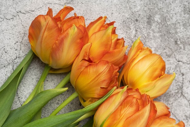 Ramo de tulipanes naranjas sobre una mesa de hormigón gris