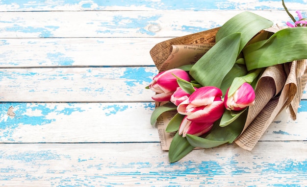 Ramo de tulipanes en un paquete de periódicos viejos sobre un fondo de madera.