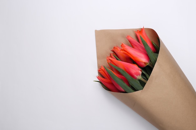 Ramo de tulipanes rojos en envases de papel en blanco