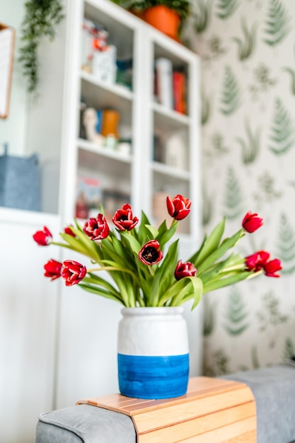 Un ramo de tulipanes rojos en un jarrón sobre la mesa en la sala de estar moderna Hermoso concepto de primavera