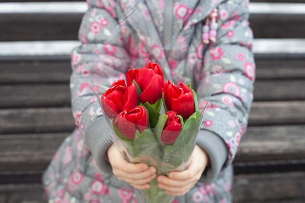 Un ramo de tulipanes rojos en manos de la niña.