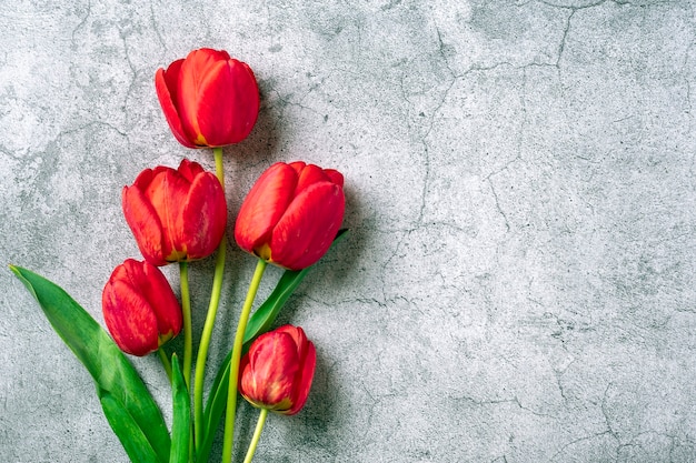 Ramo de tulipanes rojos sobre fondo de hormigón